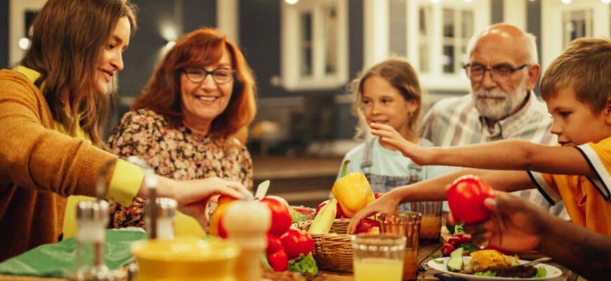 A family sitting at an outdoor patio patio table with various food and drinks on it